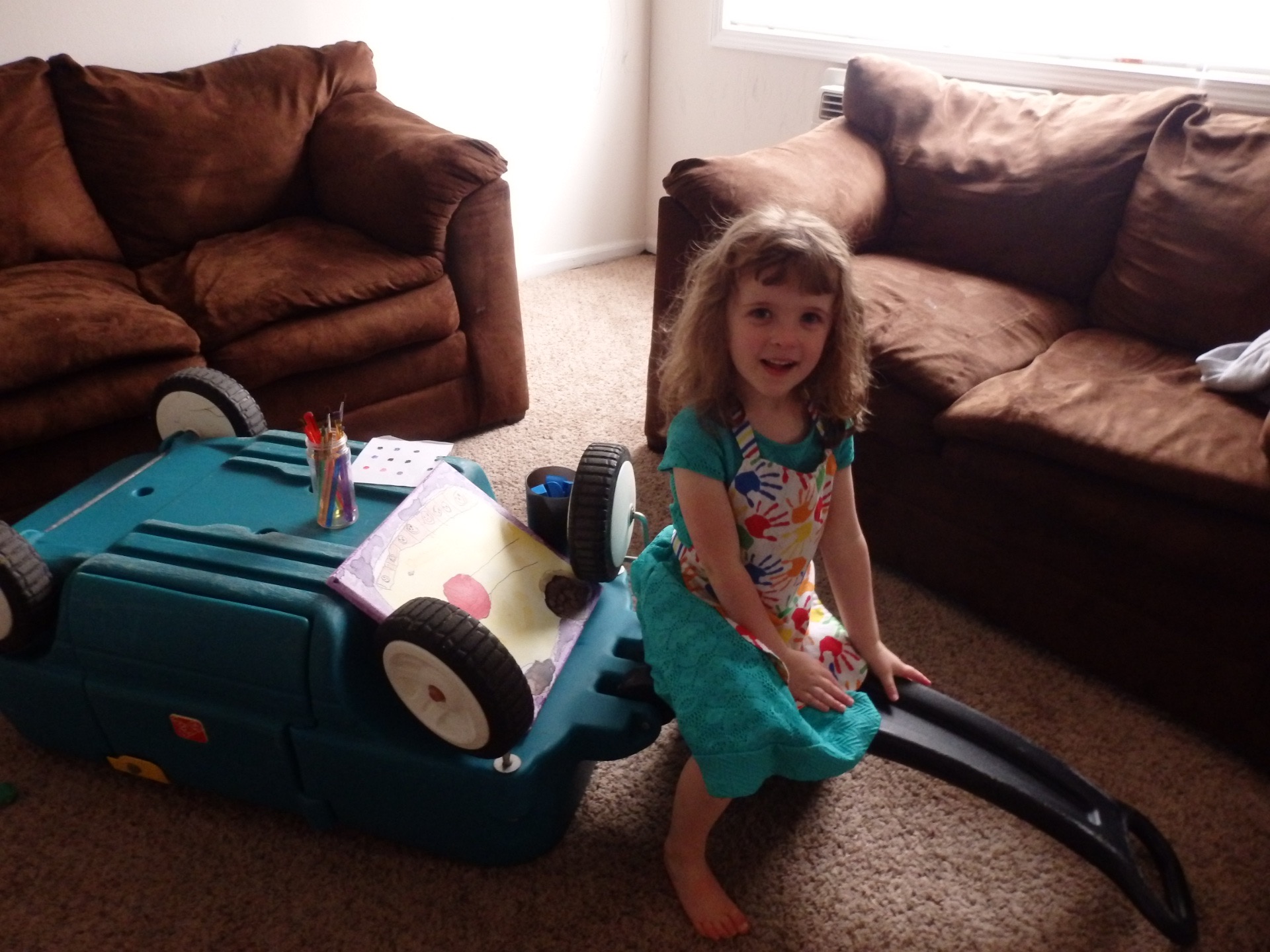 heidi with a painting, cup of paintbrushes, and a cup with blue duplos