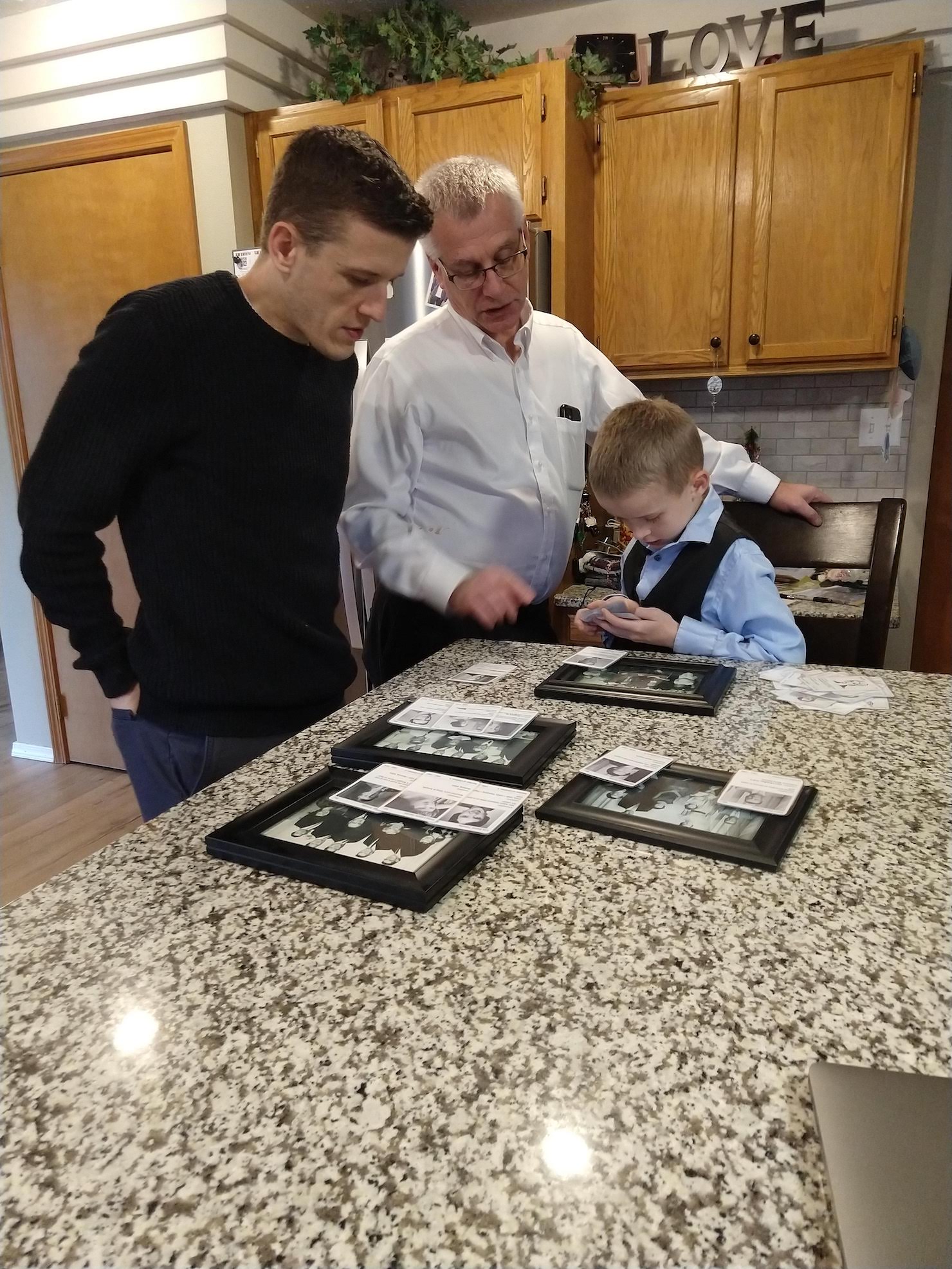 a son, a father, and a grandfather gather around the ancestor cards