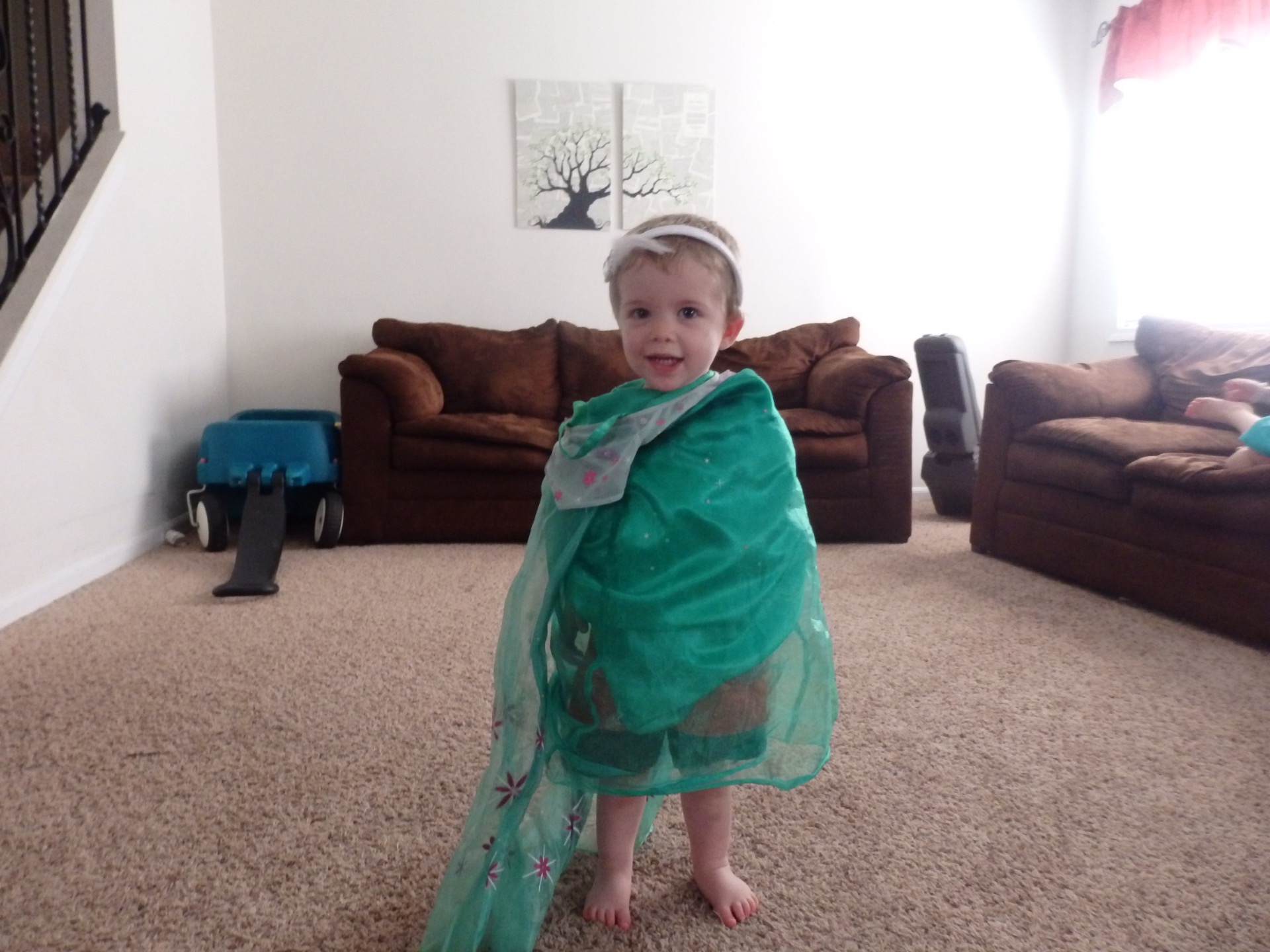 Austin with his arms pinned down inside a princess dress and with a princess headband on his head