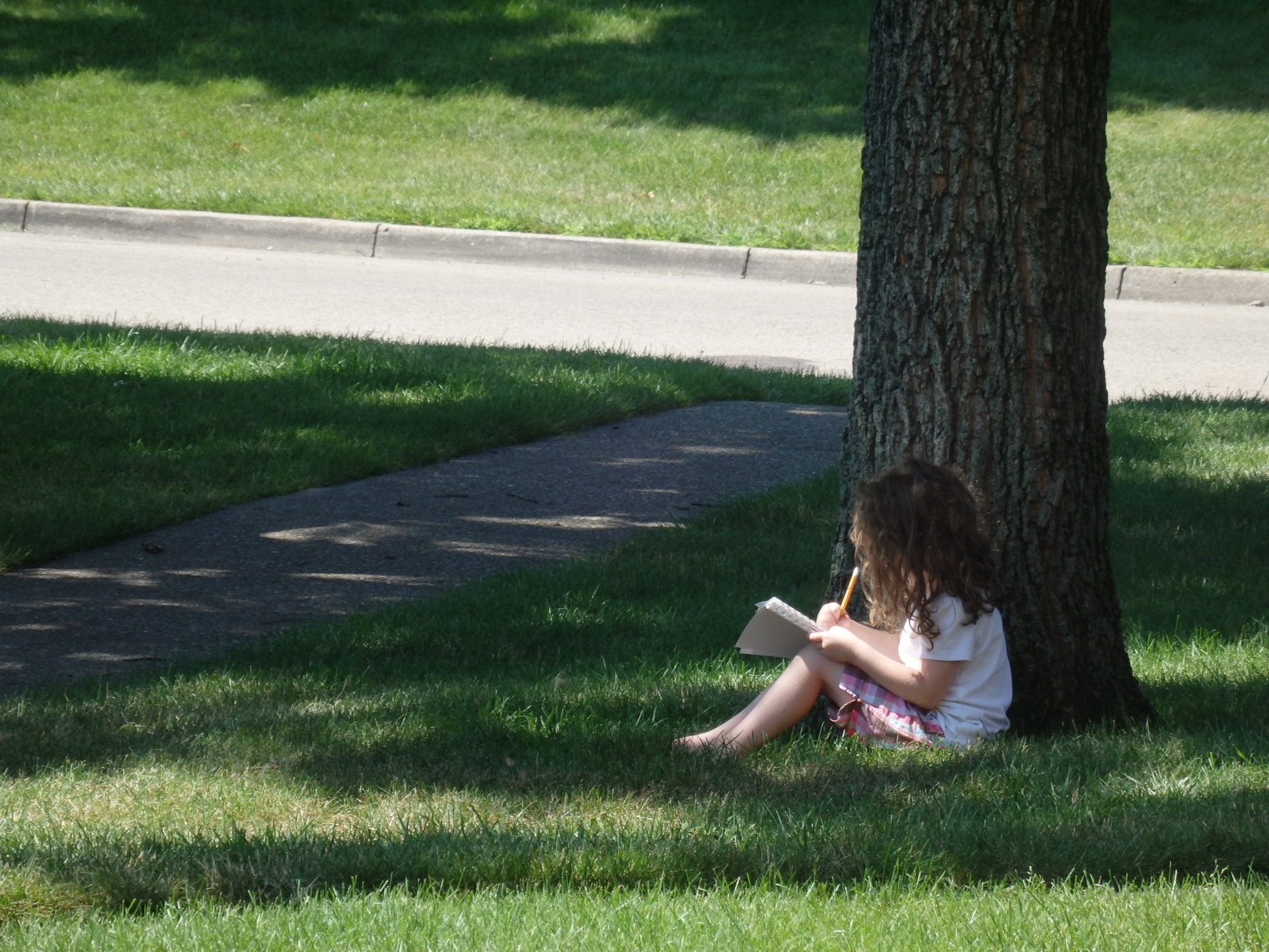 Heidi is sitting outside on a beautiful day, drawing in a sketchpad