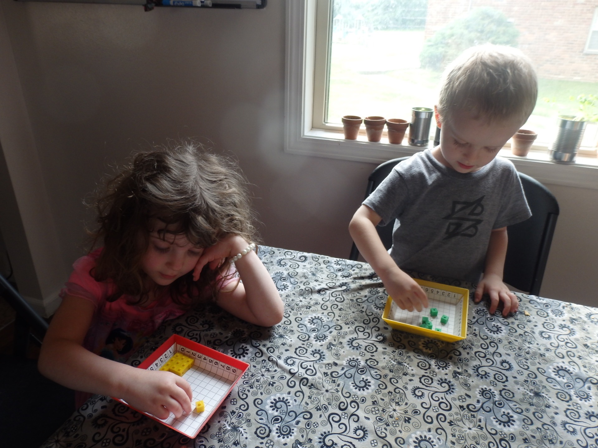 girl and boy playing with cubes in a tray