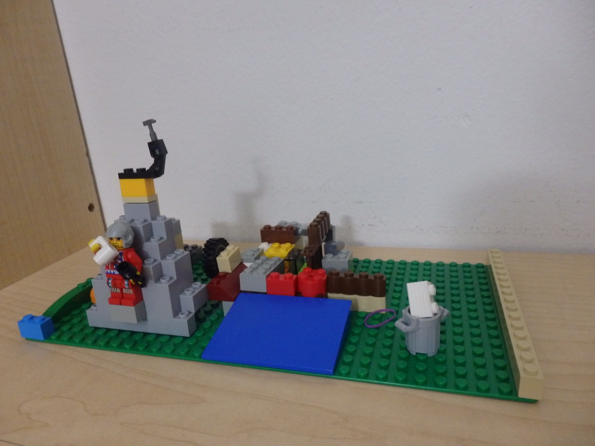 Lego figure standing on the side of a mountain with random other pieces put near it